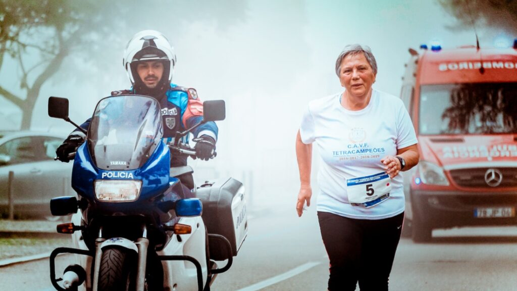 man in motorcycle escort a old woman with a red ambulance | golden hour
