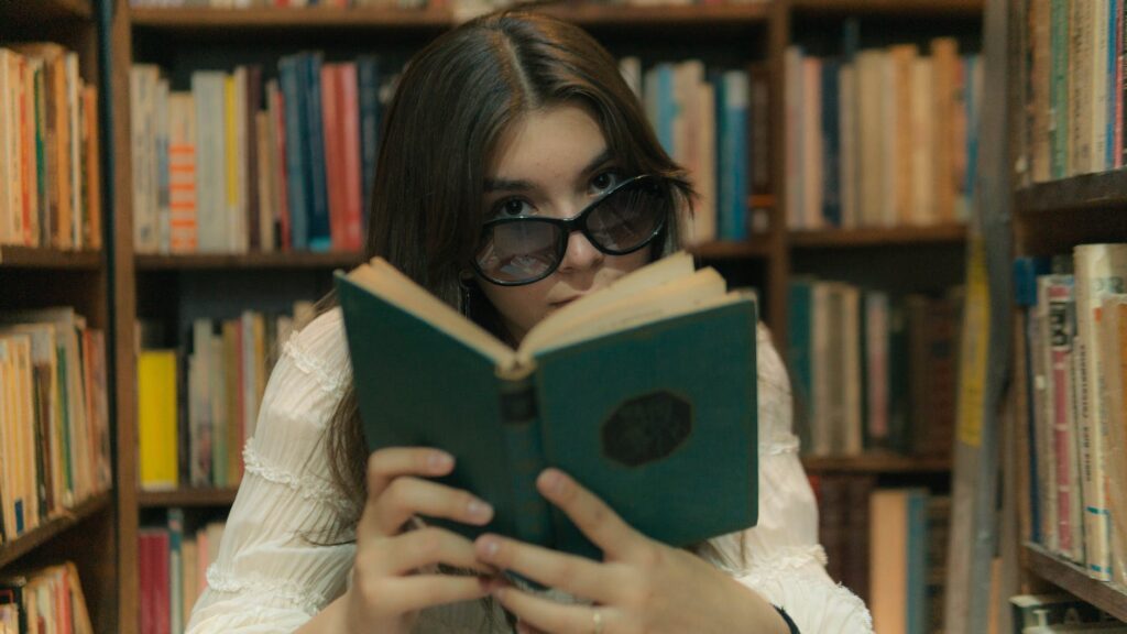 woman with sunglasses reading book in library