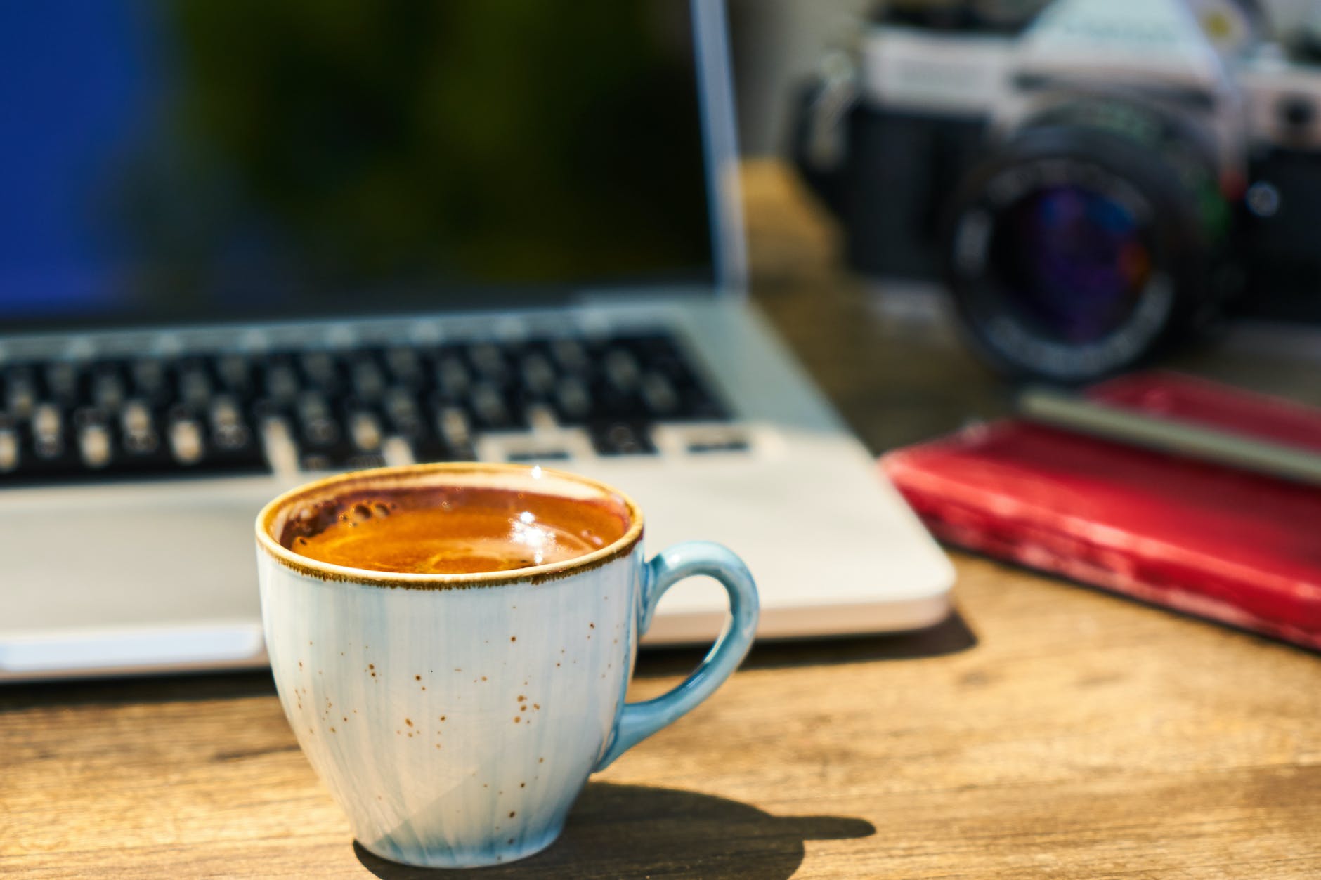 a cup of coffee and a camera on a wooden table in the workplace | Here are some popular press release sites submission