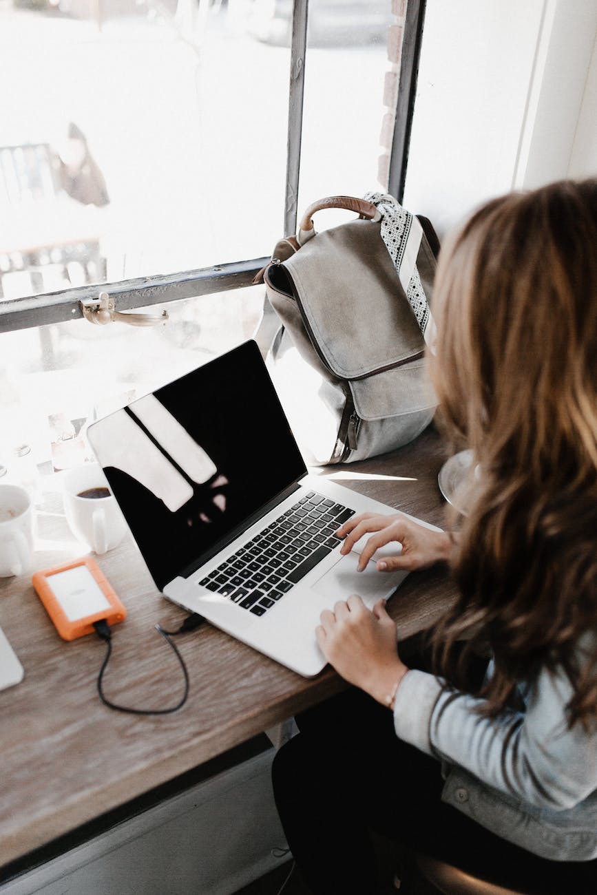 close up photography of woman sitting beside table while using macbook \ Creative writing prompts submission to i'mBiking