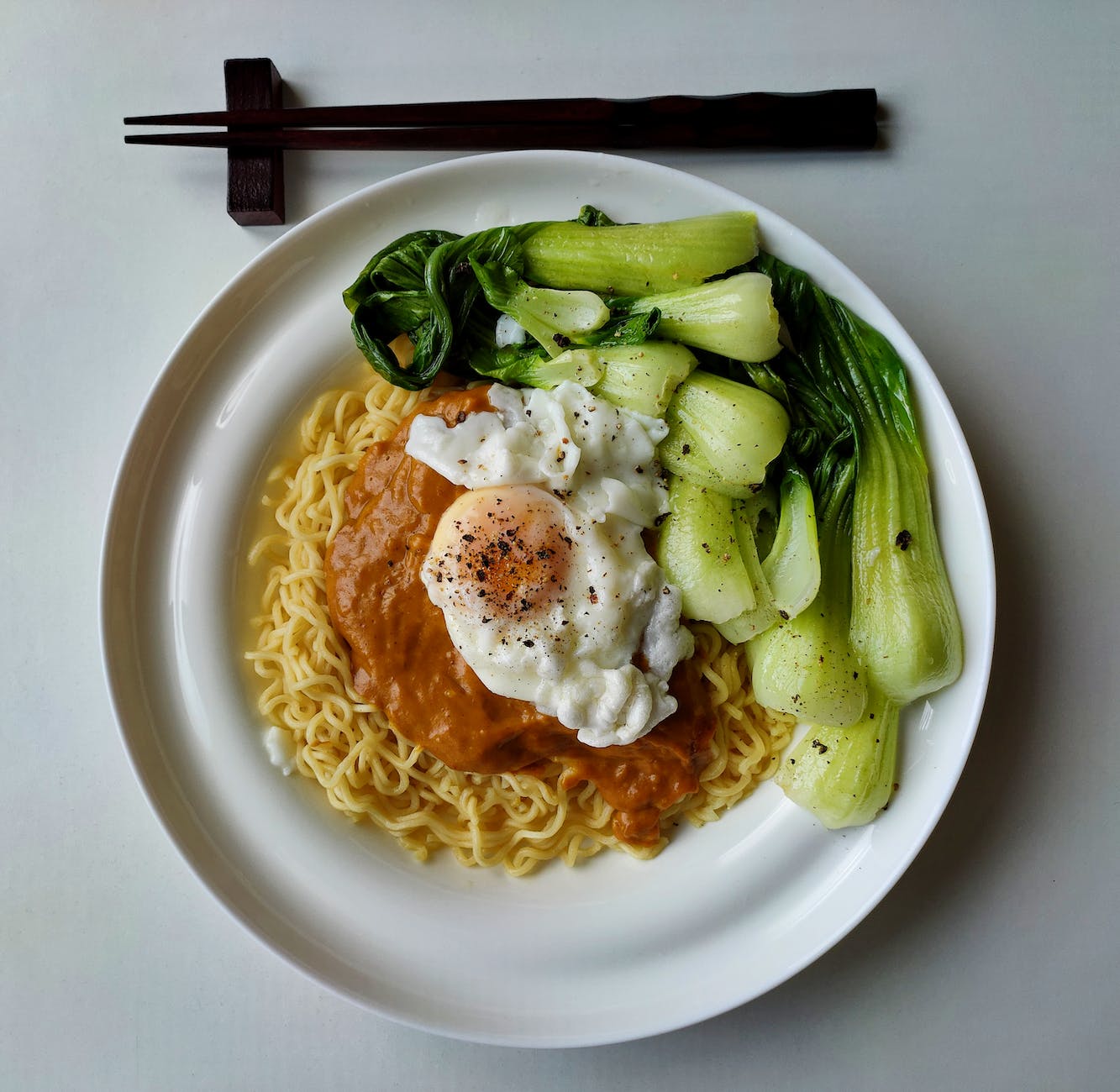 delicious noodles with bok choy and fried egg on plate | Black pepper benefits: Best health in a modern lifestyle and using it on modern food as well. Photo by Syed Muhammad Afifi on Pexels.com