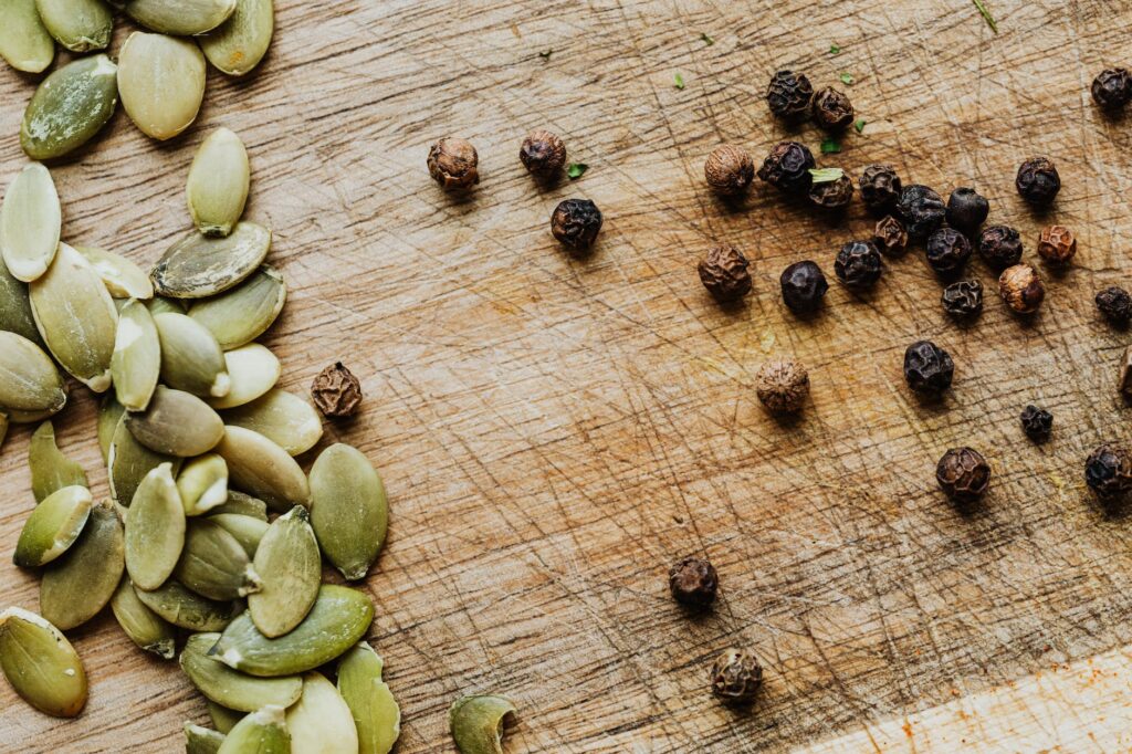 pumpkin seeds and pepper on a wooden cutting board