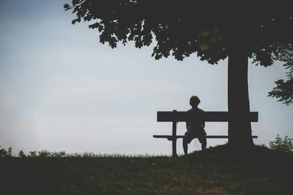 person sitting on bench under tree: Feeling like you're "too much"? You're not alone — you're exactly what this world needs. A love letter to deep feelers, dreamers, and those who care big.